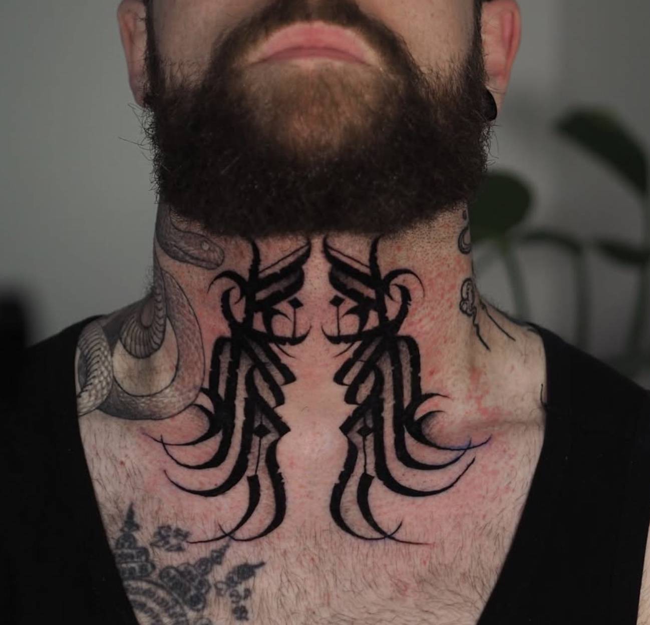 Shoulder and arm tattoo featuring a stylized abstract pattern with bold black lines